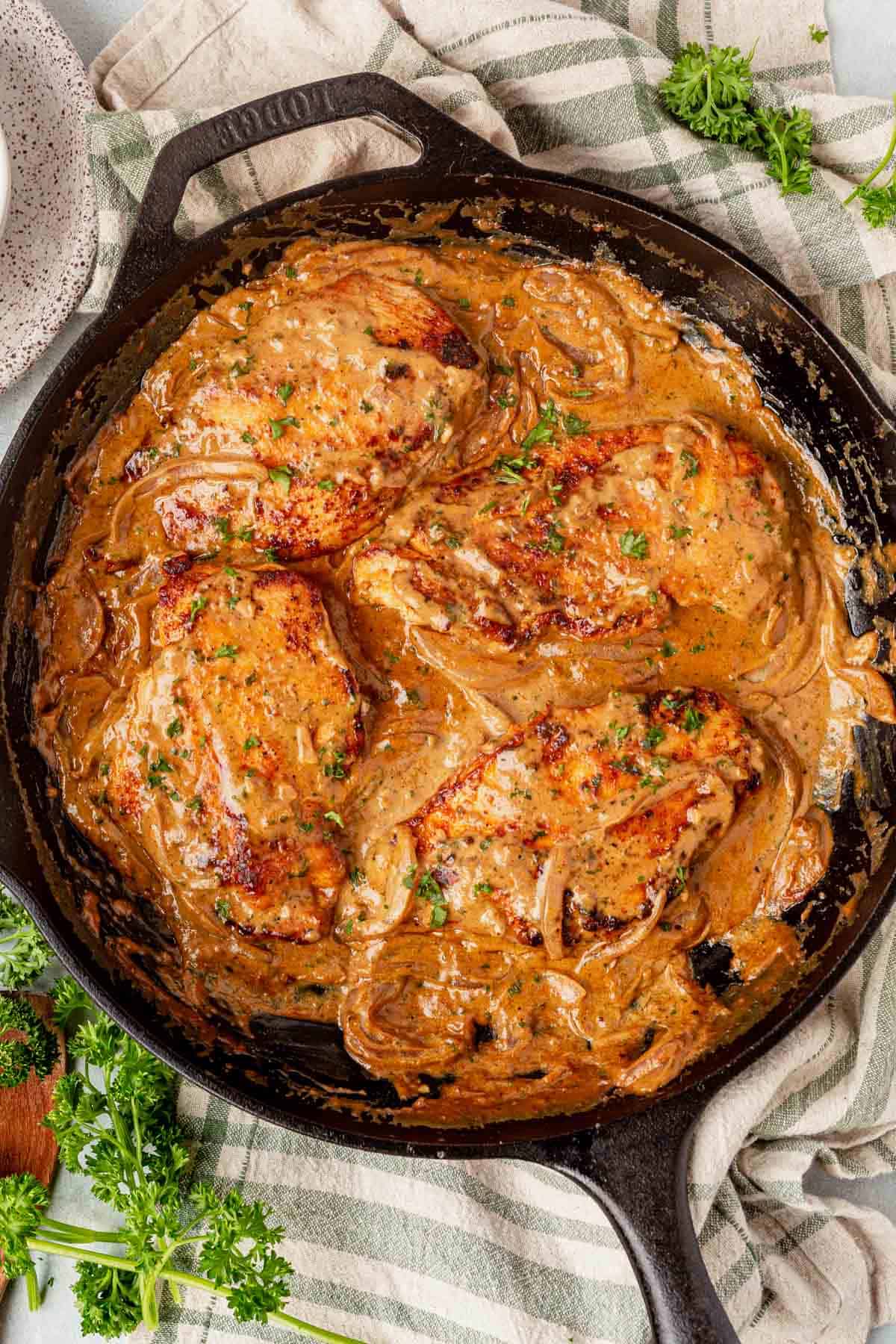 four pieces of boursin chicken in a cast iron skillet.
