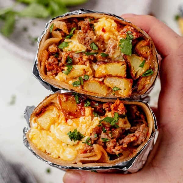 holding two halves of a chorizo breakfast burrito to see the fluffy egg, cheese, and potatoes inside
